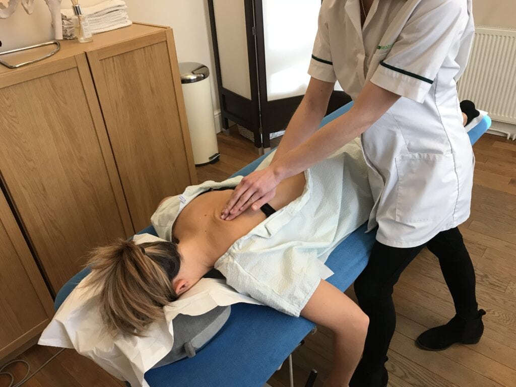 Osteopath treating upper back wearing a gown to protect modesty. Avenue Health osteopathy